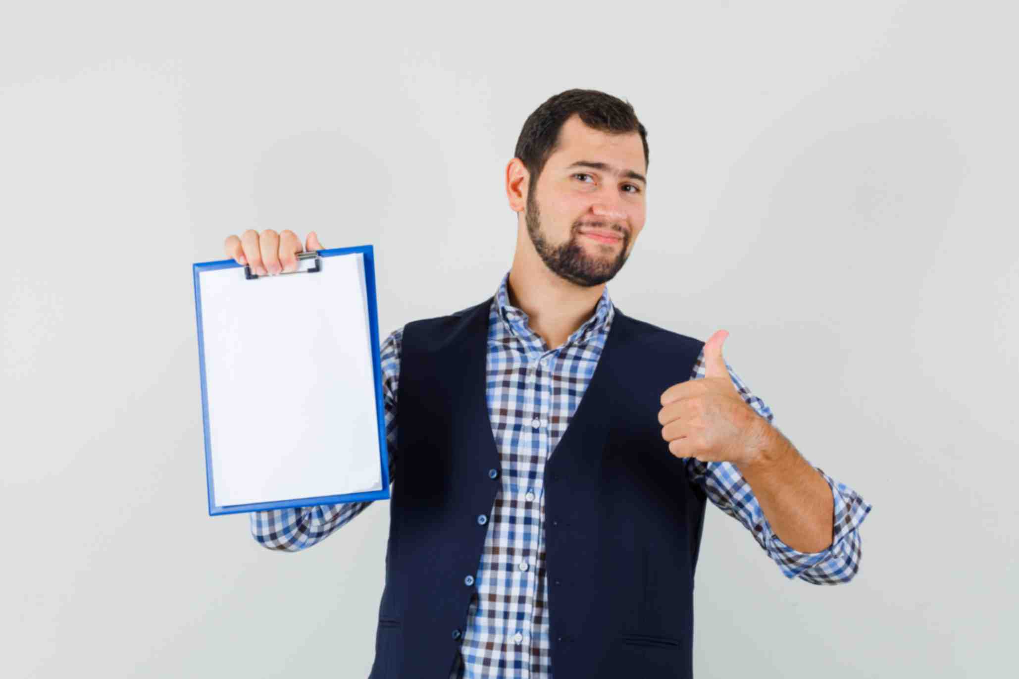 jpeg-optimizer_young-man-holding-clipboard-with-thumb-up-shirt-vest-looking-cheery-front-view