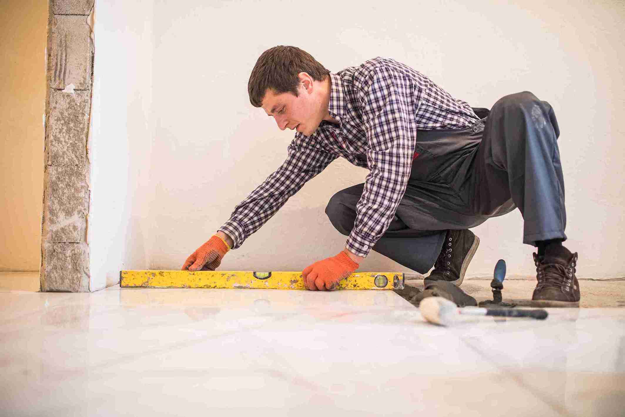 home-tile-improvement-handyman-with-level-laying-down-tile-floor_11zon