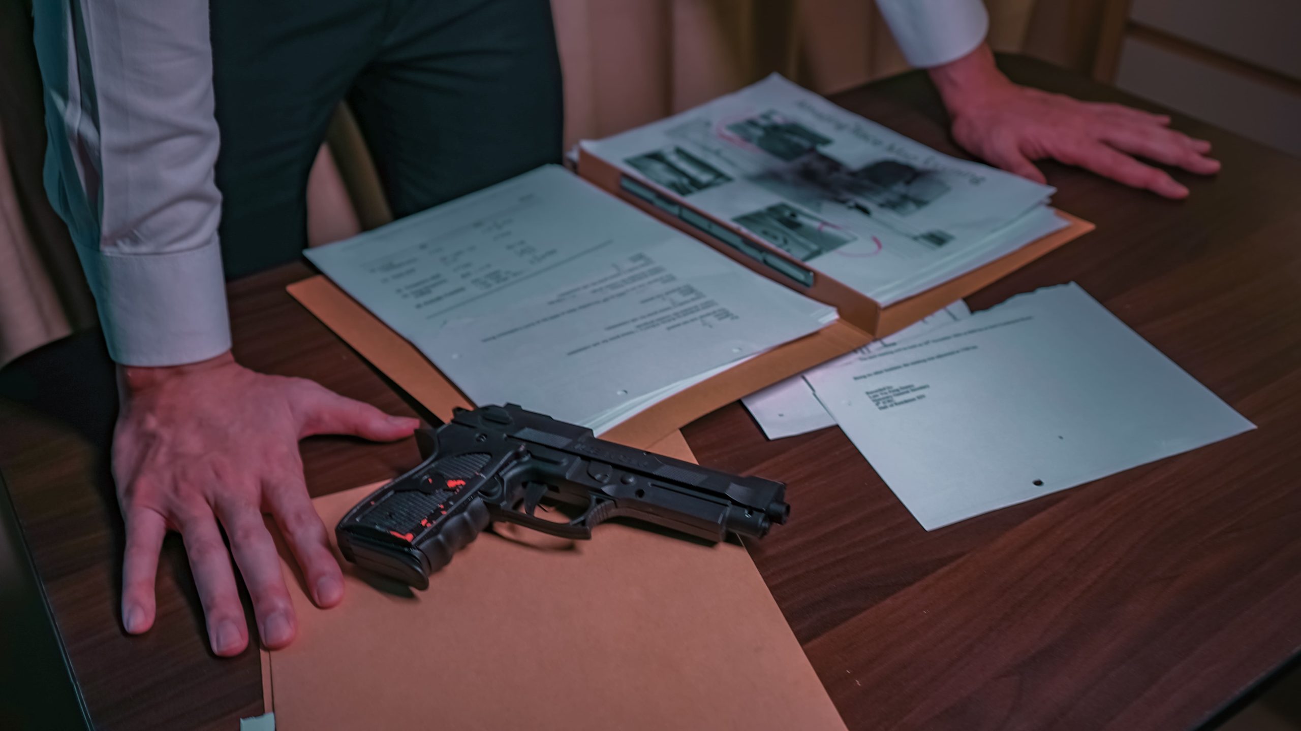 midsection-policeman-with-document-gun-standing-by-table-police-station (1)