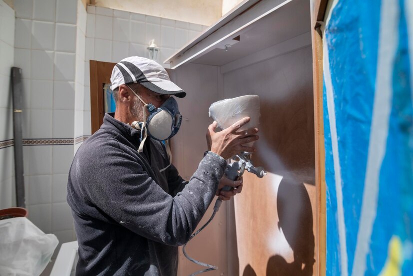 painter-working-white-wooden-furniture-from-spray-gun_628849-235
